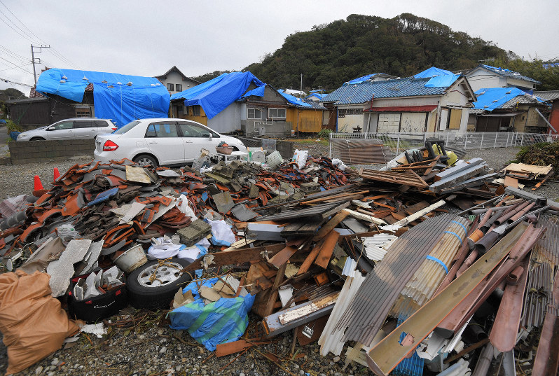 台風15号による被災から1週間が経ち、屋根のブルーシートが目立つ住宅と、空き地に集められたがれきの山=千葉県館山市布良で2019年9月16日午後2時32分、手塚耕一郎撮影