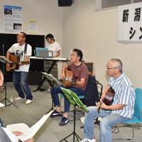 シンポジウムで応援歌を披露するオッサンバンドのメンバー＝新潟市北区の環境と人間のふれあい館で