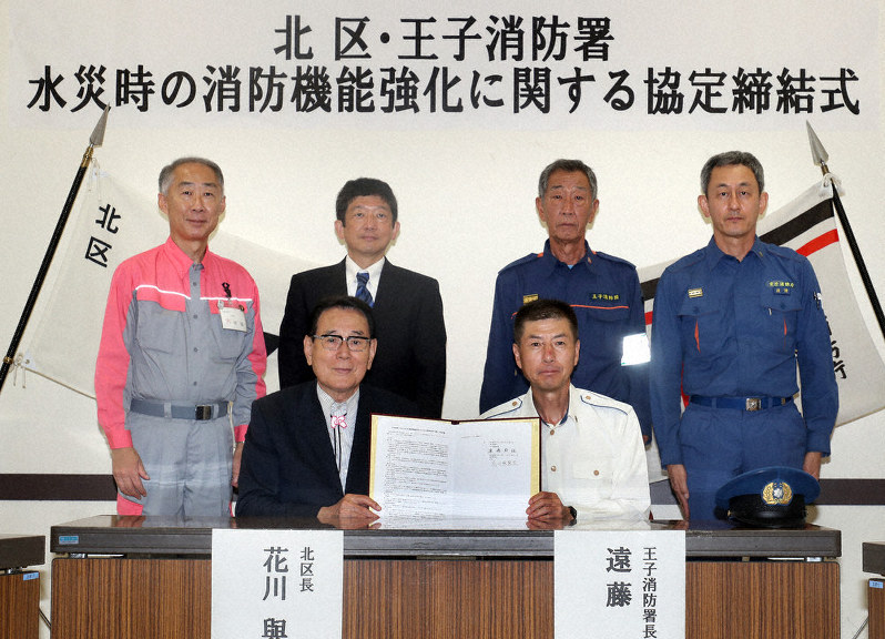 北区と王子消防署で交わされた水災時の消防機能強化に関する協定締結式で書面を交わす花川與惣太(よそうた)北区区長(左)と遠藤幹雄東京消防庁王子消防署長=東京都北区十条台1の区立中央公園文化センターで