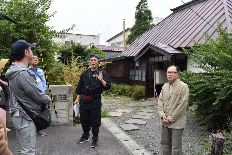 忍者屋敷とされる古民家を紹介する清川繁人教授(中央)=青森県弘前市で