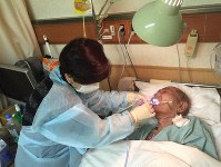 入院している父親の口のケアをする山下ゆかりさん（左）＝山下さん提供