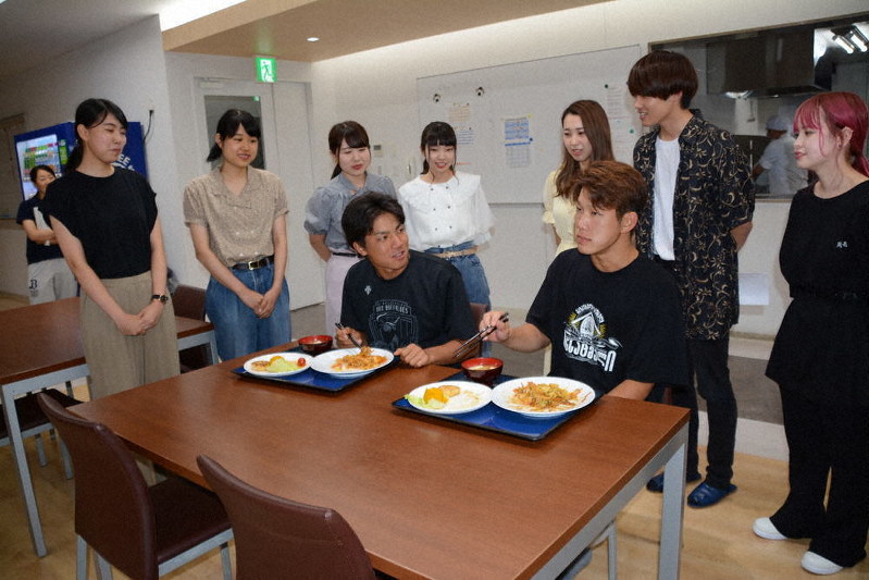 帝塚山学院大の学生が考案した食事を味わう宜保翔(手前左)と西浦颯大=大阪市此花区の「青濤館」で、球団提供