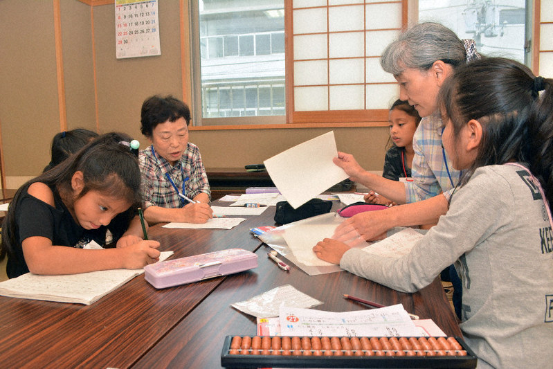 ボランティアから勉強を教わる「まるがめ子どもにほんごひろば」の子供たち=香川県丸亀市南条町の城乾コミュニティセンターで、金志尚撮影