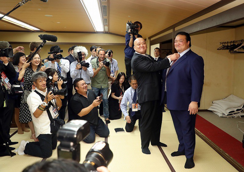 断髪式を終え、大勢の報道陣に囲まれながらスーツ姿で笑顔を見せる元横綱・稀勢の里の荒磯親方（右端）＝東京・両国国技館で２０１９年９月２９日、小川昌宏撮影                