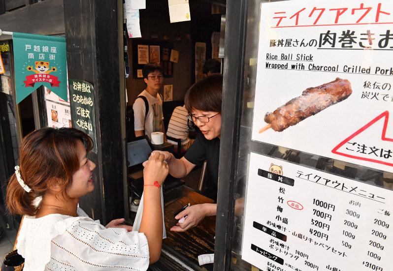 消費税率が8%のテイクアウトで商品を購入する客(手前)。後方は10%になる店内飲食の客=東京都品川区で2019年10月1日午後1時46分、大西岳彦撮影