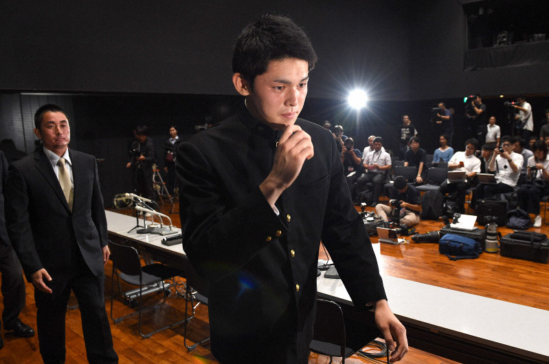 プロ志望を表明する記者会見を終え、会場を後にする大船渡高校の佐々木朗希投手。左は同校野球部の国保陽平監督=岩手県大船渡市で2019年10月2日午後6時35分、丸山博撮影
