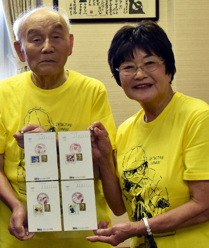 「名探偵コナン」の風景印を押したポストカードを手にする青山泰陸さん(左)、美智子さん夫妻=鳥取県北栄町由良宿の北栄町役場大栄庁舎で、小坂春乃撮影