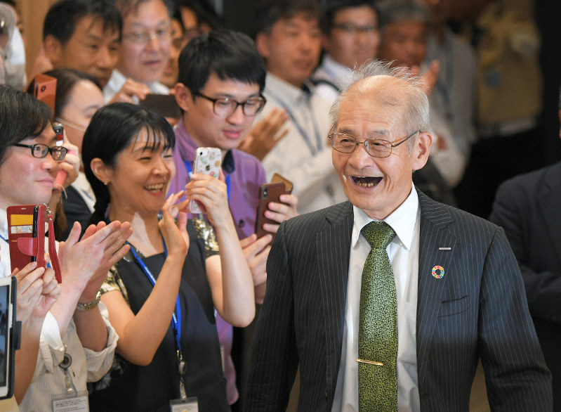 ノーベル化学賞の受賞が決まり、社員が迎える中、笑顔で記者会見場に姿を見せる吉野彰旭化成名誉フェロー=東京都千代田区の旭化成東京本社で2019年10月9日午後7時21分、手塚耕一郎撮影