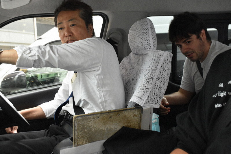 AI配車のタクシーに乗り込むイタリア人観光客(右奥)=金沢市で、日向梓撮影
