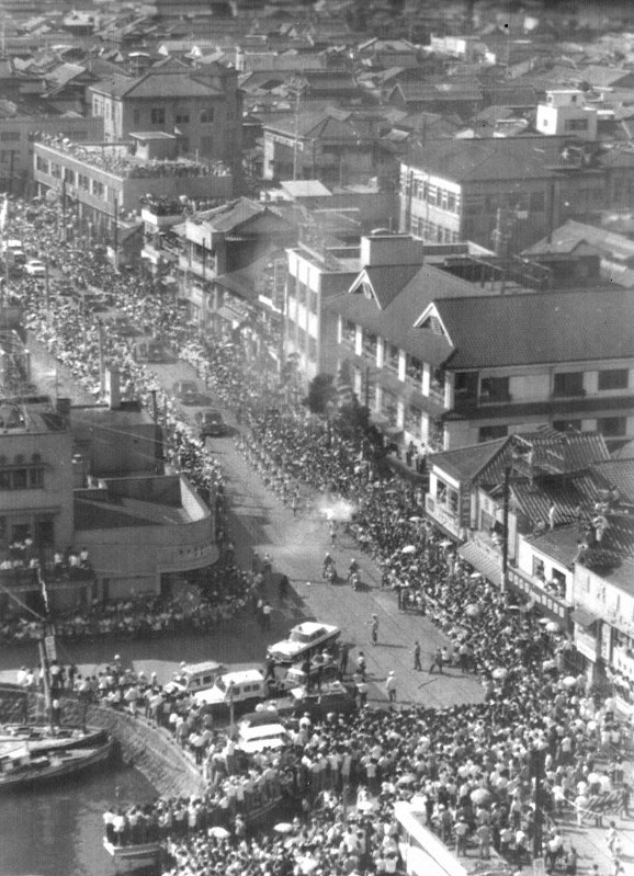楠港(当時)に到着し、人波の中を進む聖火=大分県別府市で1964年9月12日、本社ヘリ「かもめ号」から撮影