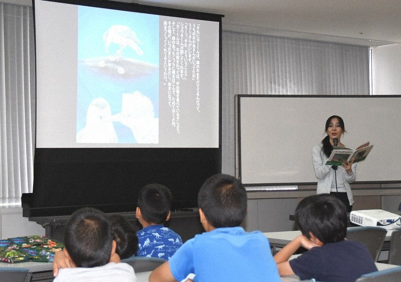 絵本「カーくんと森のなかまたち」を朗読する作者の夢ら丘実果さんと、聴き入る子どもたち=和歌山市手平2の和歌山ビッグ愛で、黒川晋史撮影