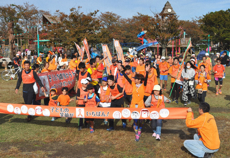滋賀県立びわ湖こどもの国にゴールしたオレンジリボンたすきリレー最終区のランナー=高島市で、塚原和俊撮影