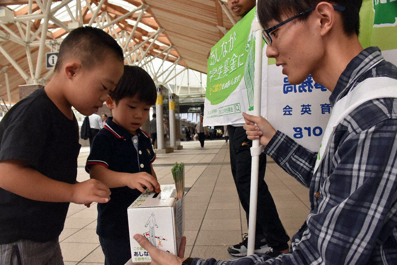 あしなが学生募金のスタッフらの呼びかけに応じて寄付をする子どもたち=JR岡山駅で、戸田紗友莉撮影