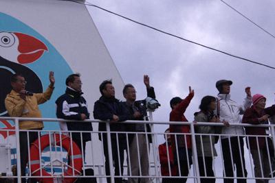 岸壁で見送る市民らに手を振る北方領土観光ツアーの参加者＝北海道根室市の根室港で２９日午後２時５９分