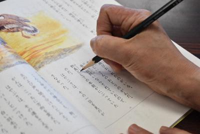 フィリピン人の男児の教科書に振り仮名をつける特別支援学級の女性教諭。外国籍の子どもの指導は教諭によって差が出る＝関東地方の小学校で、鈴木敦子撮影