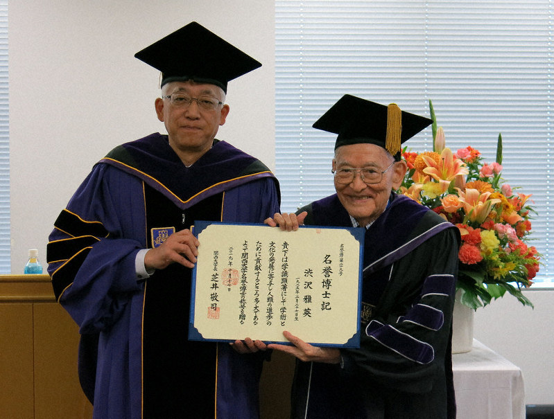 関西大の芝井敬司学長(左)から贈られた名誉博士号を手にする渋沢栄一記念財団の渋沢雅英理事長=東京都千代田区丸の内1の関西大東京センターで、中根正義撮影