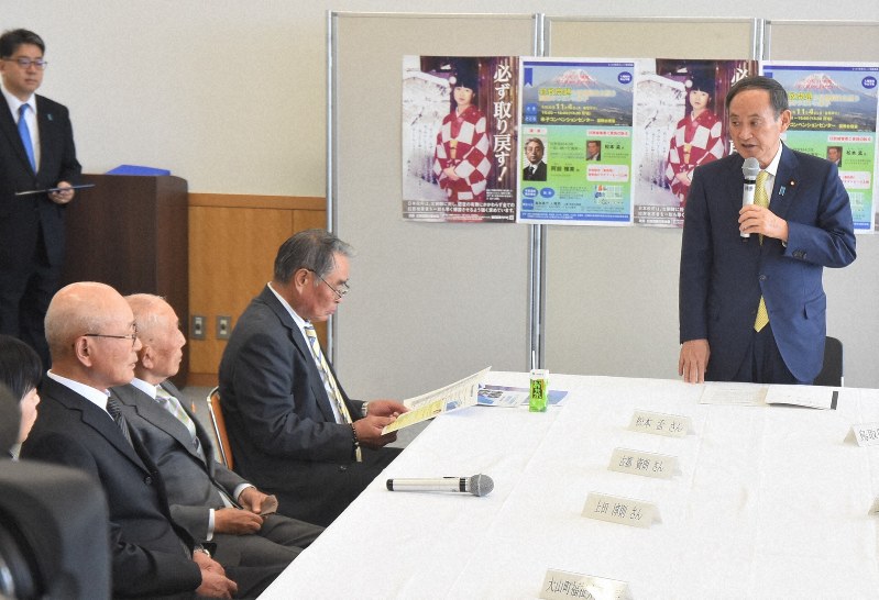 鳥取県米子市の米子コンベンションセンターで、拉致問題担当相を兼ねる菅義偉官房長官(右)の話を聞く拉致被害者や特定失踪者らの家族3人=2019年11月4日午後、秋山信一撮影