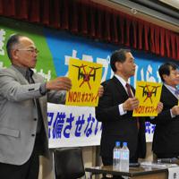 反対集会でプラカードを掲げる古賀さん（左）ら