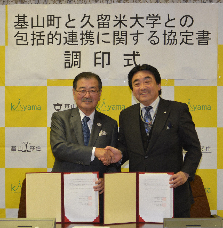 協定書に調印し、握手を交わす永田学長(左)と松田町長