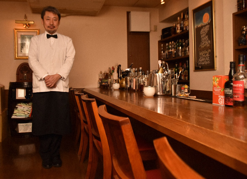 車いす利用者でも使いやすい低めのバーカウンターを横に立つ関元さん=白川徹撮影