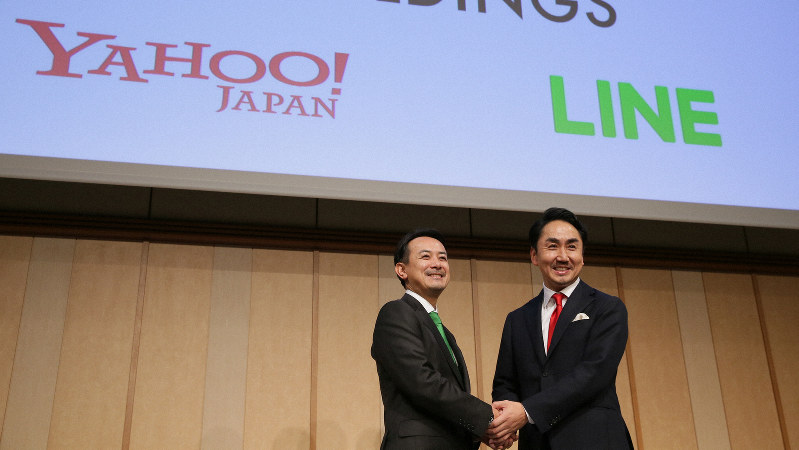 経営統合の記者会見で、笑顔で握手するZホールディングスの川辺健太郎社長(左)とLINEの出沢剛社長=東京都港区で2019年11月18日、吉田航太撮影