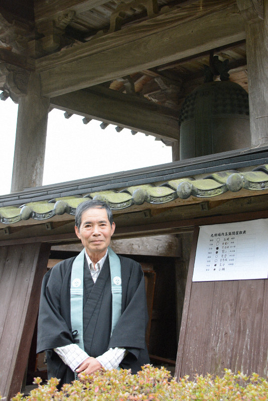 玉鷲の白星を祝う鐘を突いている明元寺の佐々木幸哉住職。鐘の傍らには、玉鷲の勝敗を記す紙を張っている=福岡県朝倉市で2019年11月18日午前8時55分、黒川優撮影