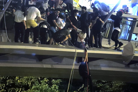 Protesters use ropes to lower themselves from a pedestrian bridge to waiting motorbikes in order to escape from Hong Kong Polytechnic University and the police in Hong Kong, Monday, Nov. 18, 2019. (AP Photo/Kin Cheung)
