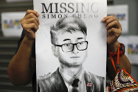In this Aug. 21, 2019 file photo, a supporter holds a poster outside of the British Consulate in Hong Kong during a rally in support of a consulate employee who was detained while returning from a trip to China. (AP Photo/Vincent Yu)