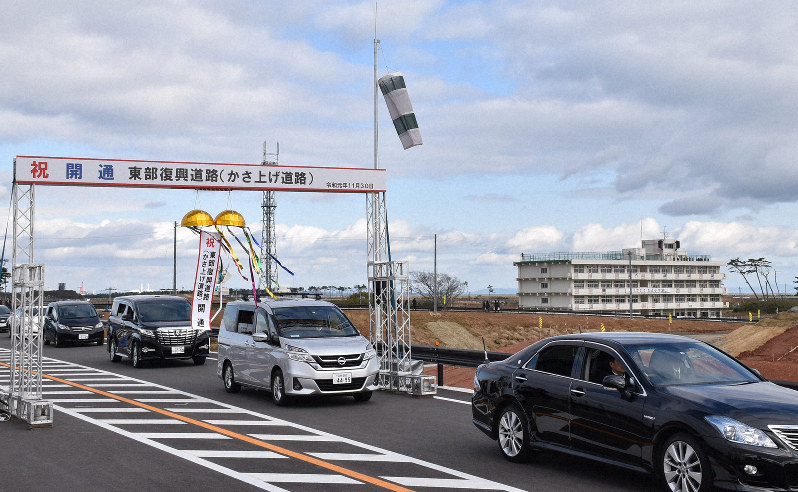 東部復興道路の通り初めをする車列。後方には震災遺構の荒浜小が見える=仙台市若林区で2019年11月30日、滝沢一誠撮影