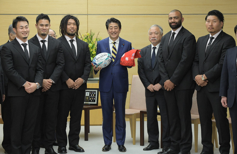 ラグビー・ワールドカップ日本大会日本代表のリーチ・マイケル主将(右から2人目)らから記念品を贈られる安倍晋三首相(中央)=首相官邸で2019年12月11日午後5時20分、川田雅浩撮影