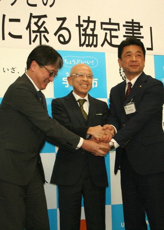 協定書に調印し手を取り合う(右から)守田市長、佐藤社長、三輪局長