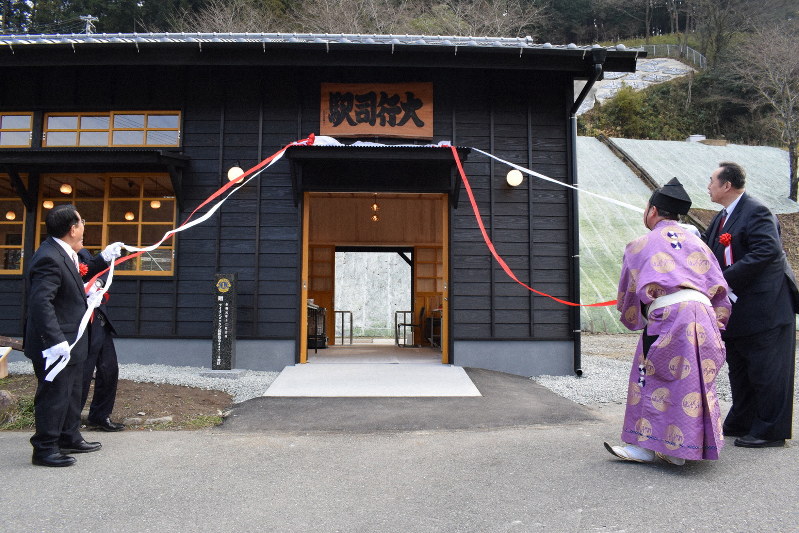 復元新築されたJR大行司駅舎の看板を除幕する渋谷博昭村長(左)と芝田山親方(右)、式守伊之助さん(右から2人目)ら=福岡県東峰村で2019年12月21日