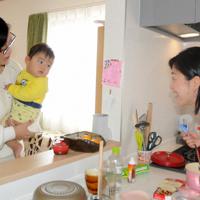 赤ちゃんに声をかけながら調理するサポーター(右)=東京都江戸川区で