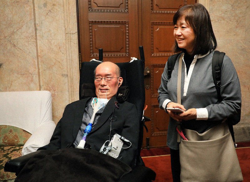 参院本会議場を後にし、笑顔を見せる舩後靖彦さん(左)と介助する佐塚みさ子さん=国会内で2019年12月9日、梅村直承撮影
