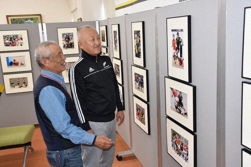 山口高ラグビー部の活躍の軌跡がわかる写真展会場と撮影した日報連会員の松岡さん(左)