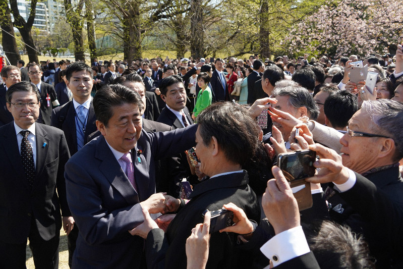 「桜を見る会」の参加者と握手をして回る安倍晋三首相(左)=東京都新宿区の新宿御苑で2019年4月13日(代表撮影)