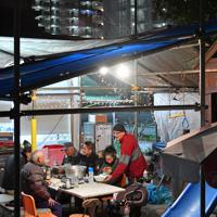 コンビニエンスストア脇の「潮芦屋げんきCafe」で談笑する復興住宅の入居者たち。奥には復興住宅が見える＝兵庫県芦屋市で2020年1月1日、山田尚弘撮影