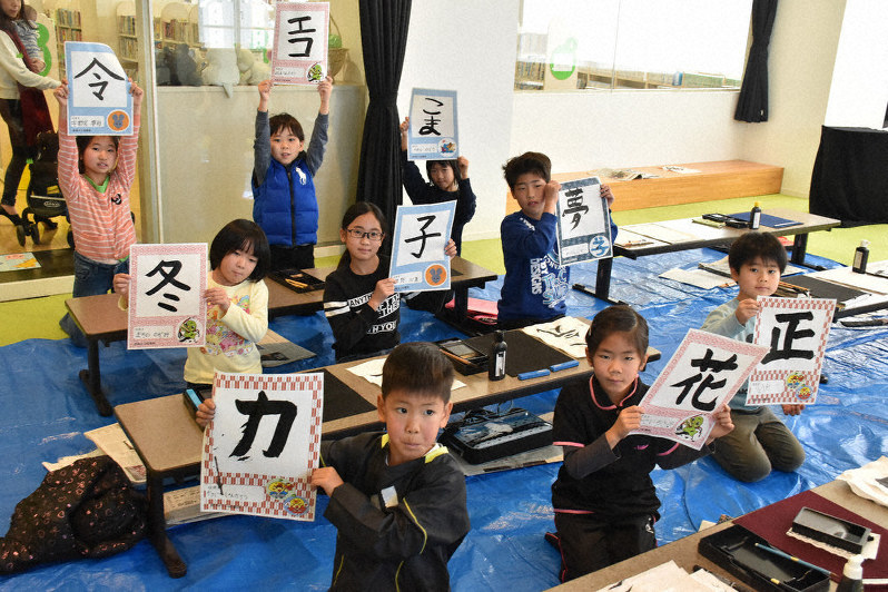 自分で書いた習字を持つ小学生ら=徳島市立図書館で、松山文音撮影