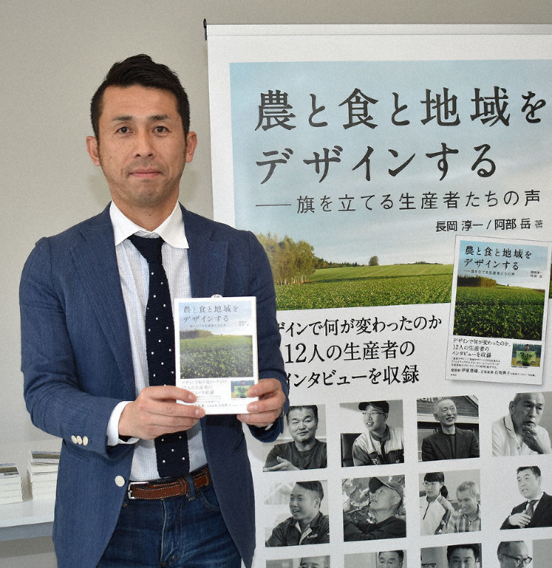 生産現場のデザインの意義をまとめた本を手にする長岡淳一社長=北海道帯広市で