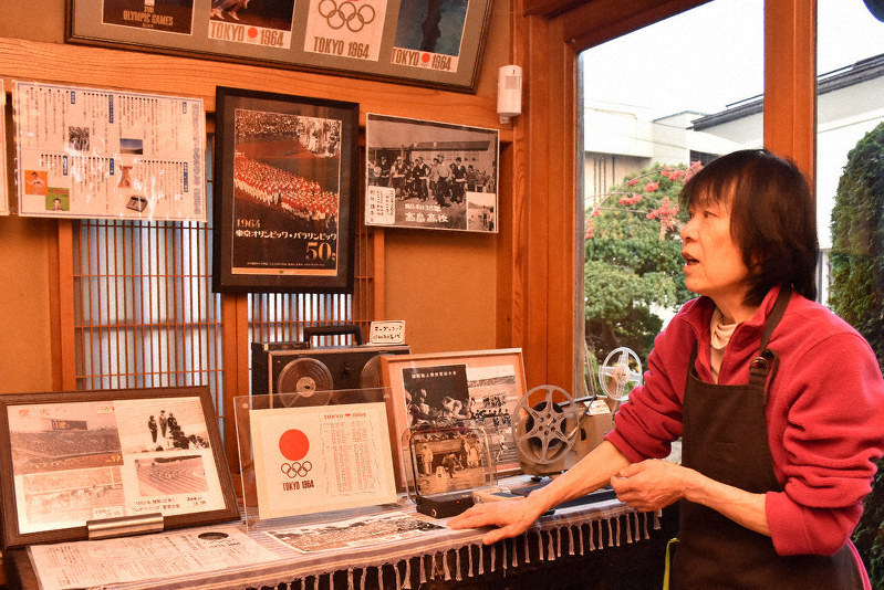 店の一角にある1964年東京五輪の資料について話す伊沢まき子さん=高畠町で