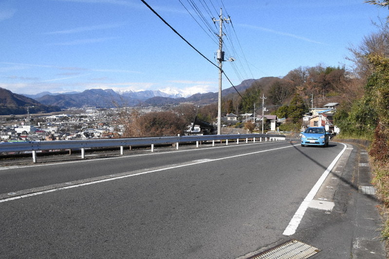 回想シーンで親友同士の少年2人が自転車で駆け下りる「滝坂」。中央奥に白銀に覆われた谷川岳