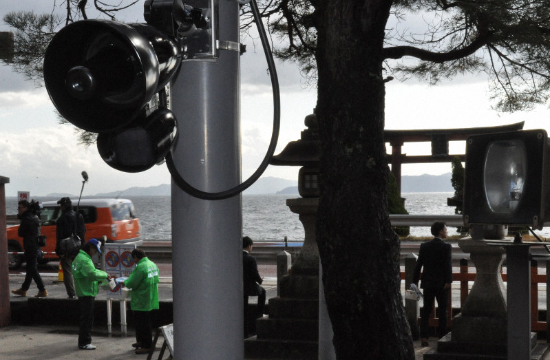 白鬚神社に設置された装置(手前左)。琵琶湖上の大鳥居(右奥)目当ての観光客に「国道の横断は危険」と呼び掛ける=滋賀県高島市で2020年1月8日午前11時10分、塚原和俊撮影