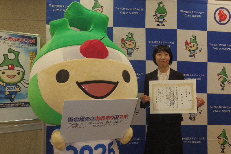 第80回国民スポーツ大会の愛称とスローガンの規定書体を掲げるマスコットキャラクターの「アップリート君」(左)とイメージソングの歌詞に選ばれた井元仁江さん=青森市のホテル青森で2020年1月14日、井川加菜美撮影