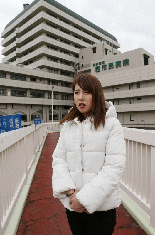 阪神大震災の当日に生まれた江口愛恵美さん。奥は神戸市立医療センター西市民病院=同市長田区で2020年1月12日、大西達也撮影