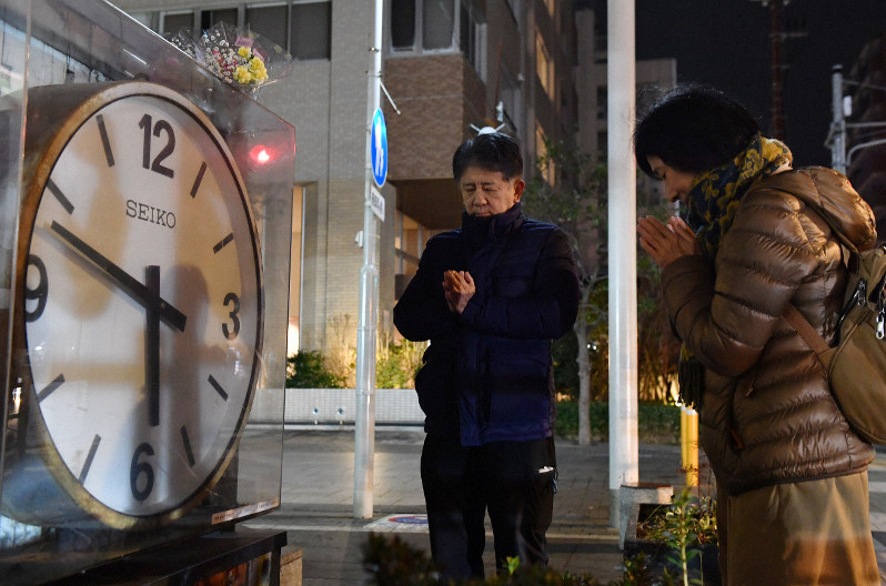 発生時刻で止まったままの時計の前で手を合わせる人たち=兵庫県西宮市で2020年1月17日午前5時46分、猪飼健史撮影
