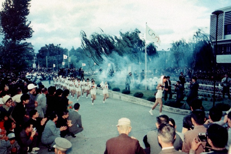 大勢の市民が待つ中、松本市役所に到着した東京五輪の聖火ランナー=1964年10月5日(逸見泰明さん提供)