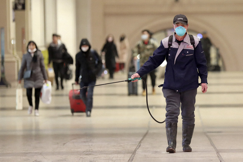 駅で消毒剤をまく職員=中国湖北省武漢市で22日、AP (Chinatopix via AP)