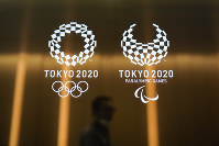 In this June 11, 2019 file photo, a man walks past the 2020 Olympic and Paralympic logos in Tokyo. (AP Photo/Jae C. Hong)