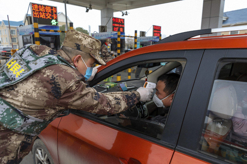 高速道路の料金所で、デジタル体温計を使い運転手の体温を測る民兵=中国湖北省武漢で1月23日、AP
