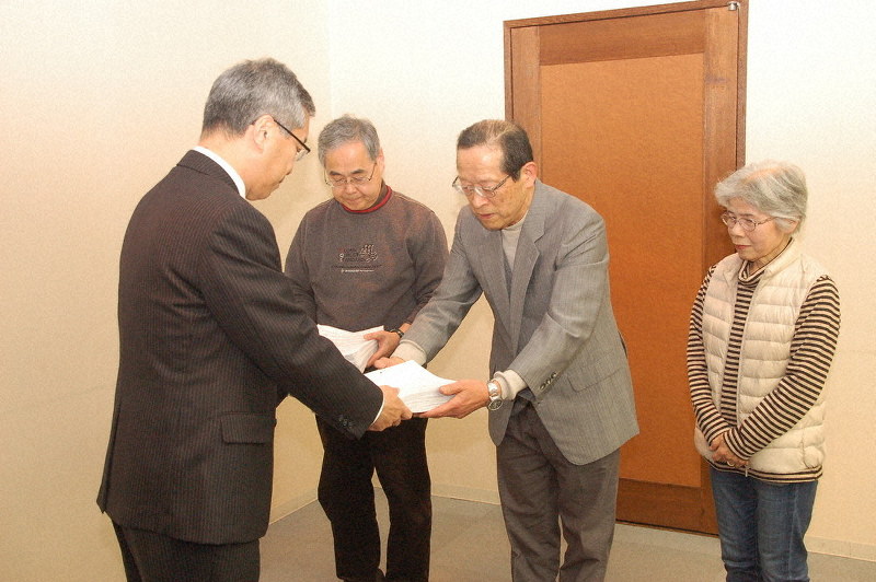 スズキへ企業立地補助金を交付しないことを求める4408人の署名を静岡県浜松市の長田繁喜副市長(左)に提出する市民グループ=同市役所で